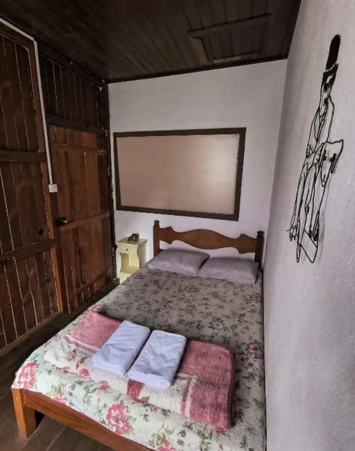 Apartamento casal com paredes de madeira e cama com colcha florida