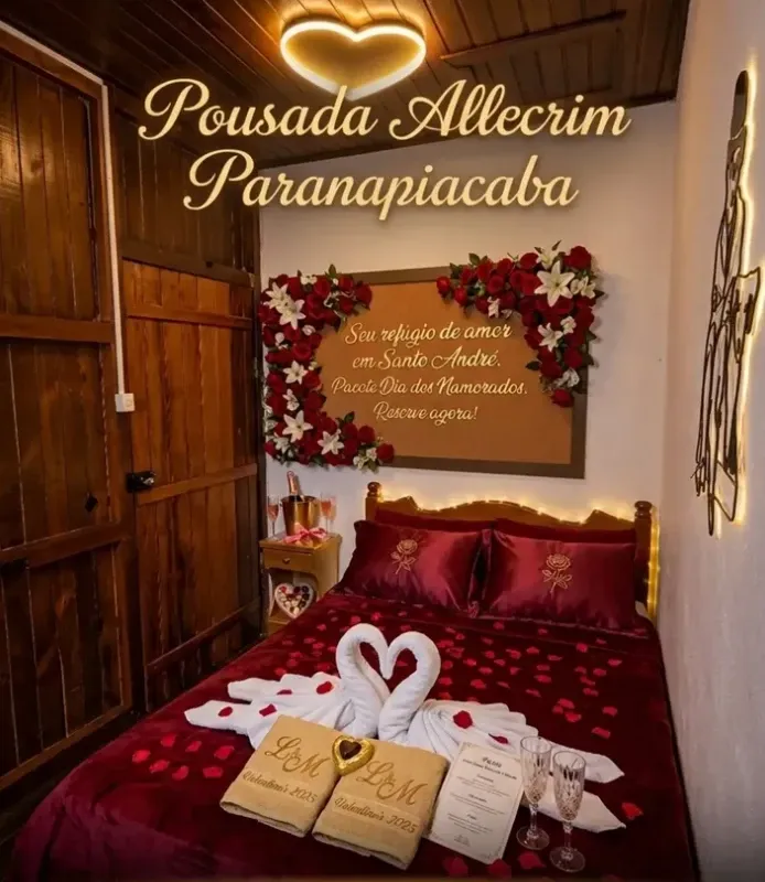 Quarto decorado para casal com pétalas de rosa, cisnes de toalha e espumante